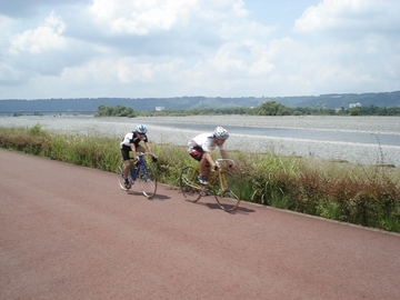 自転車を漕ぐ二人の横に川が見える