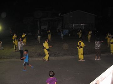 黄色い浴衣を着て盆踊りを楽しむ人々