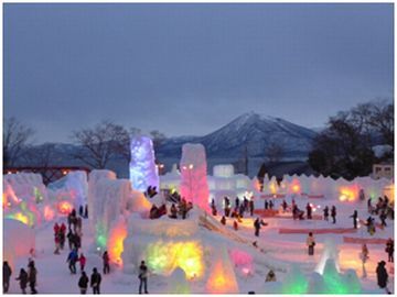 まわりが薄暗くなり、氷でできた氷像が様々な色でライトアップされている会場と多くの来場者の様子