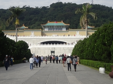 台湾の国立故宮博物院。その前の道を歩く人々、左右には剪定された木々が立ち並び後ろには山が見える