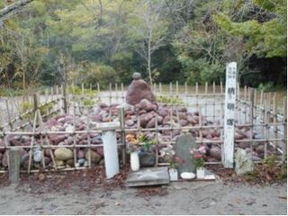 小豆色の小石がつみあげられ、周りを低い柵で囲まれた清明塚の石の様子。