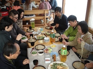 テーブルを囲みざる蕎麦を食べる人たちの画像