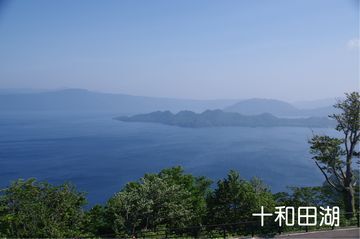 峠から見下ろす十和田湖の写真。湖の向こうの山々まで見渡せる。