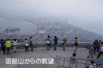 函館山からの景色。多くの観光客と少し霞がかかった函館の街が写っている。