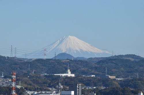 下に山や鉄塔が見え、真ん中に大きな富士山が見える写真