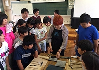 伝統工芸体験教室で人間国宝の大角幸枝先生に教えてもらっている子どもたちの写真