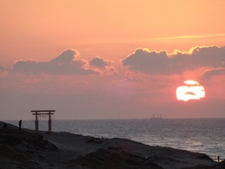 夕日に赤く染まる空と海と鳥居の写真