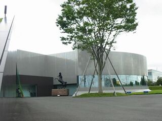 円形型の建物と出入口の前に1本の木が目を引く資生堂アートハウスの写真