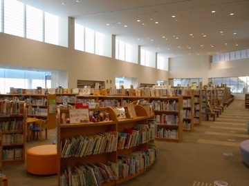図書館の一角を撮った写真。本棚が並び、手前に子供向けの本棚や、子供用の机やいすが写っている。