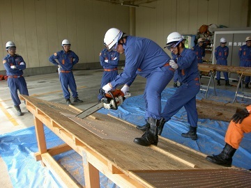 救助訓練のためチェーンソーで板を切る消防団員