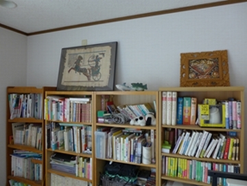 4台の本棚が並び、本棚の上に絵の入った楽屋飾りが置いてある壁の写真