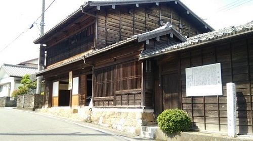 木造こげ茶色の川坂屋家屋の画像。大きな引き戸の玄関の古民家