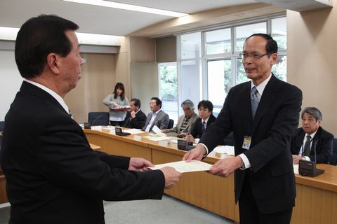 松井市長から委嘱書を受け取る鈴木委員とそれを眺める男性達