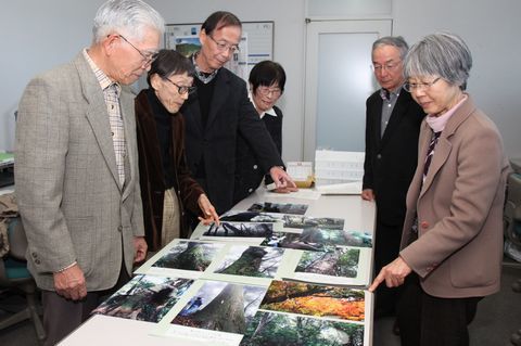 机に並べられた粟ヶ岳山頂付近で発見した巨樹の写真をみるひとたち