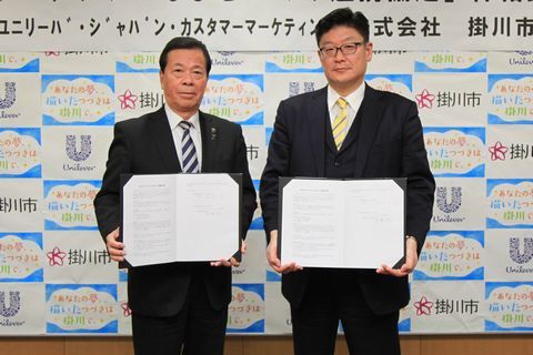 並んで協定書を胸に掲げている髙橋社長と松井市長の写真