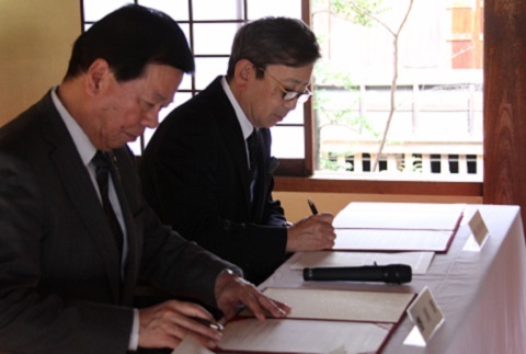 松井市長と佐々木社長が協定書にサインをしている様子