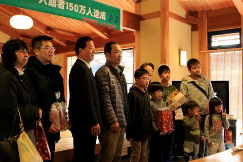 入場者150万人達成の横断幕の前で、記念写真を撮る松井市長と高橋さん家族と前後賞の方たち