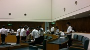 議会室にて市議会議員から議員席のあたりで一般質問の仕方を説明して確認している子ども議員たちと市議会議員たち