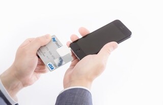 右手にスマートフォン、左手にクレジットカードの写真