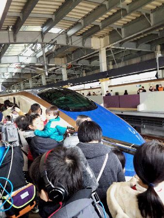 金沢駅プラットホームに並ぶたくさんの人たちと新幹線