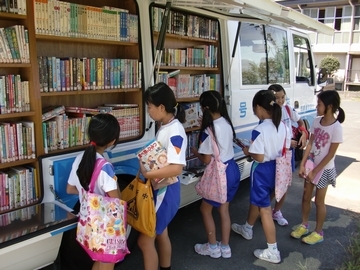 移動図書館車に並んだ本を選んでいる子供たちの画像
