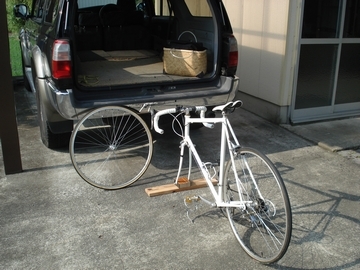 ハッチを開けた車の手前に白い自転車がある画像