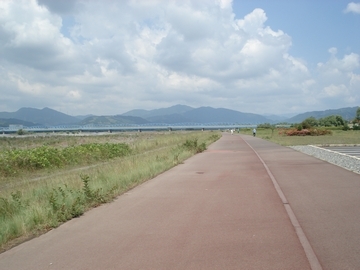 長く続くコースの向こうに橋と青空が見える画像