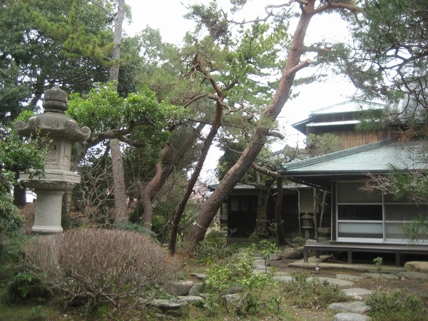 松ヶ岡の主屋と松の木や石の灯籠がある庭園