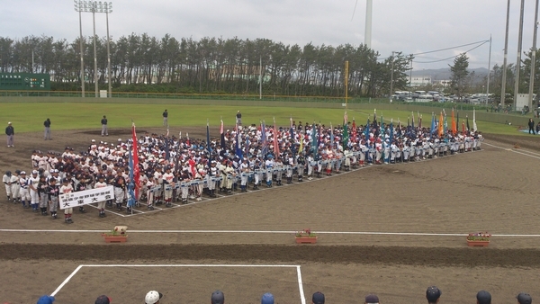開会式。野球場のグラウンドに一列に参加する野球チームが整列している