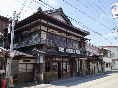 古い商家。一際特徴的な建物の老舗割烹旅館の八百甚。入母屋屋根の下に廻る庇、二階の高欄、意匠を凝らしたガラス戸