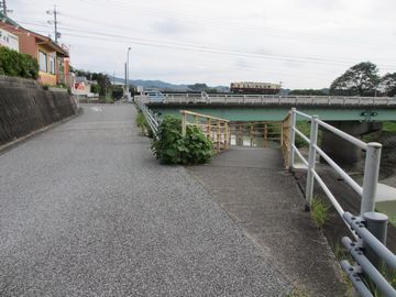 川沿いへ伸びていく道とまっすぐ伸びる道の分岐点。遠くには小さく電車が走っているのが見える。