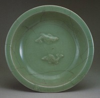 中央に魚が二匹泳ぐ丸い青土色の盤の画像