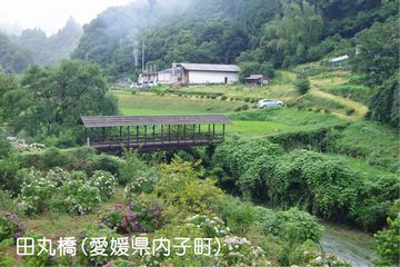 山あいの川に掛かる屋根付きの橋。奥には民家が見える。