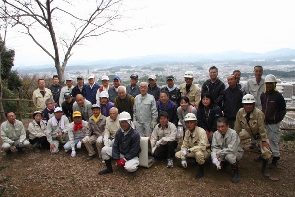 作業着、ヘルメットを被った人らが並んでこちらを見ている写真