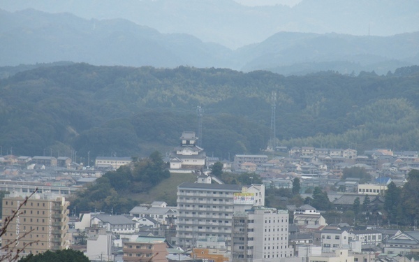 沢山のビル、建物より高い場所にある掛川城。奥には山が見える。