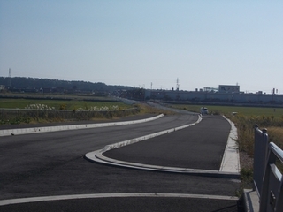 広い畑の真ん中にコンクリートで舗装された道路の写真