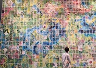 壁一面に色とりどりのデザインがされている作品を見ている人の写真