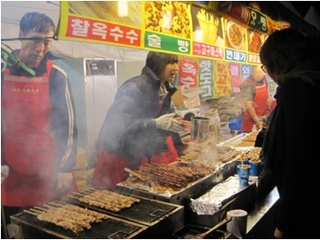 韓牛祭の画像で、屋台で串焼きを焼いている