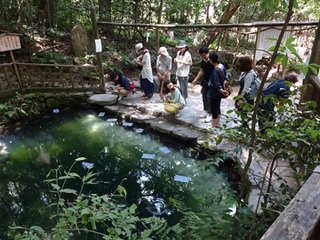 池に占い用紙を浮かべて、鏡の池の縁占いをしている人たちの画像