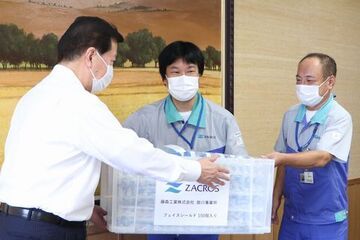 藤森工業株式会社の掛川事業所長の藤野勝之さんから、フェイスシールドを受け取っている松井市長