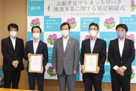 男性5人がマスクを付けて並んでいる。2人が協力事業者書を持っている