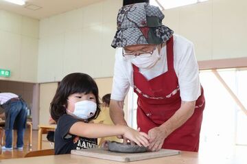 クラブ会員のおばあちゃんに手伝ってもらいながら園児がp皿を作っている