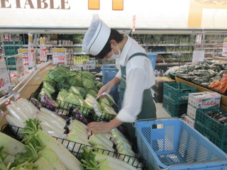 スーパーの野菜売り場で作業をしている落合さんの写真