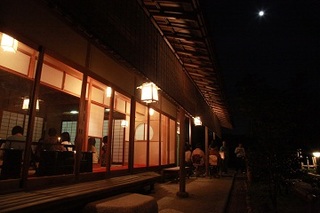 十五夜の満月を楽しむ参加者らを庭から見た写真