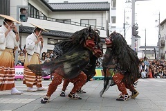 太鼓と笛似に合わせて2頭の獅子が道中で舞っている様子