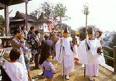 白い衣装を着た神職と神事を見守る人々