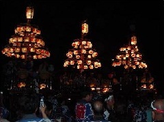 夜、提灯をつけた山車が3台並んでいる