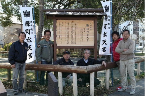 水天宮の由来を書いた立派な手作りの看板と携わった有志たち
