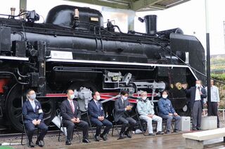 保存されている蒸気機関車の塗り替え完了記念で機関車の前で挨拶を述べている戸田会長