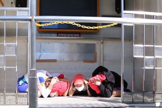 防災意識を高めるため起震車に乗り地震の時に床に身をかがめて両手で頭を守っている児童たち